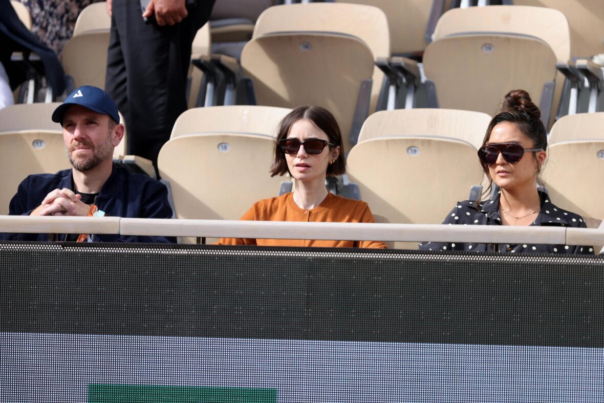 Charlie McDowell and Lily Collins sitting with Ashley Park at the stands during the French Open tennis tournament