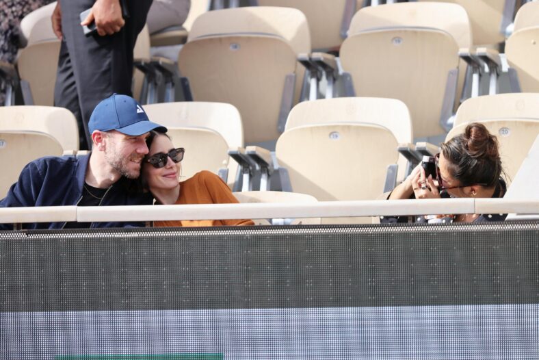 Charlie McDowell and Lily Collins sitting with Ashley Park at the stands during the French Open tennis tournament